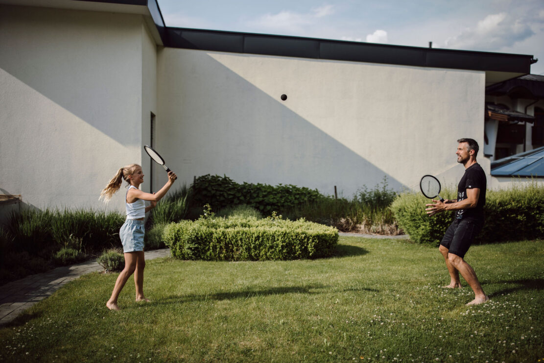 Vater und Tochter spielen auf der Liegewiese ein Ballspiel.
