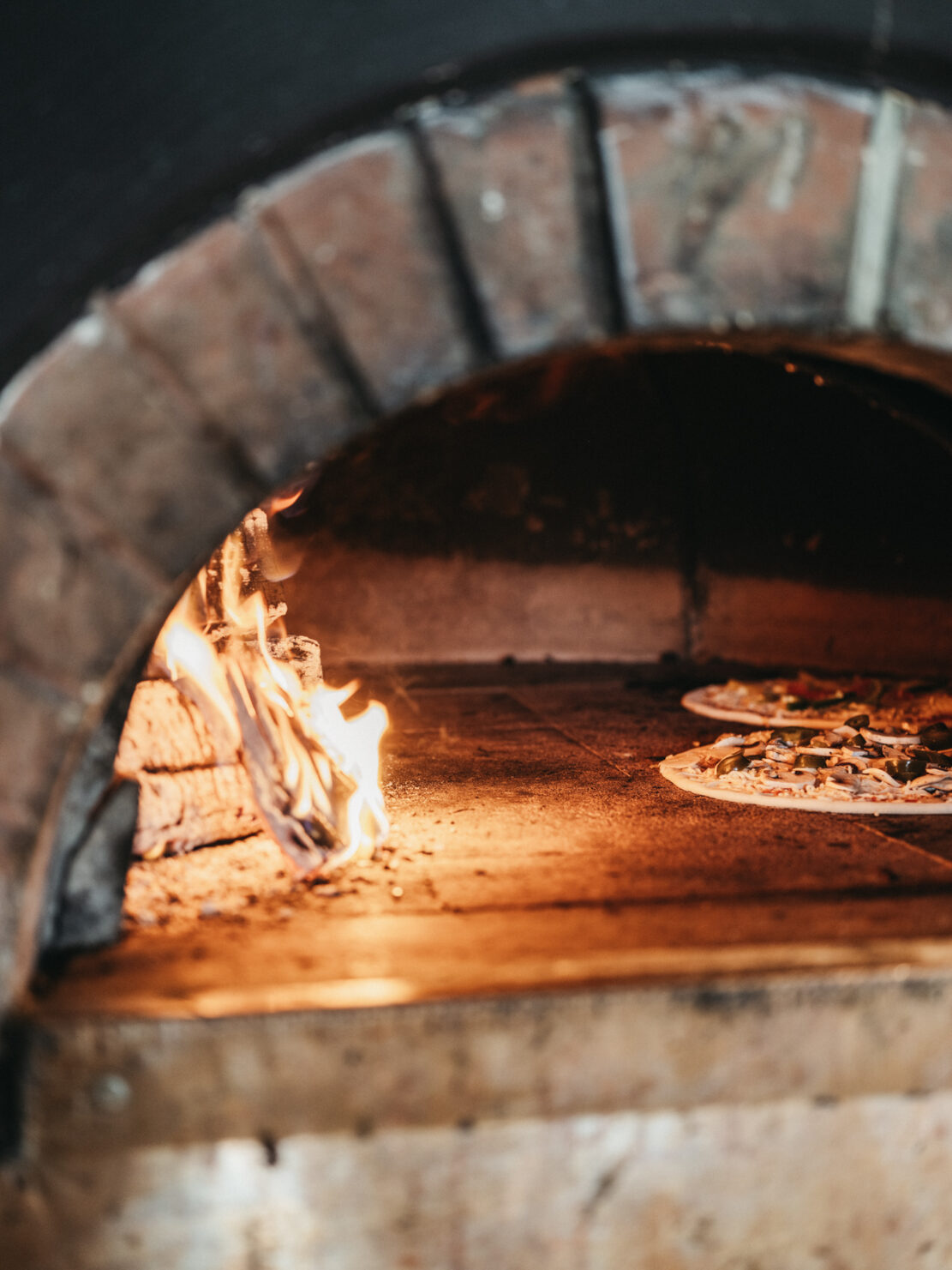 Pizzakoch beim backen einer Holzofen Pizza im BistrO Alpendorf