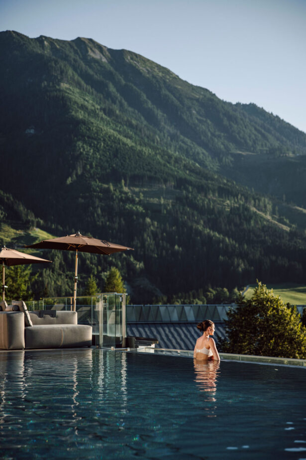 Frau genießt Aussicht im Rooftoppool im Alpina Alpendorf im Salzburger Land