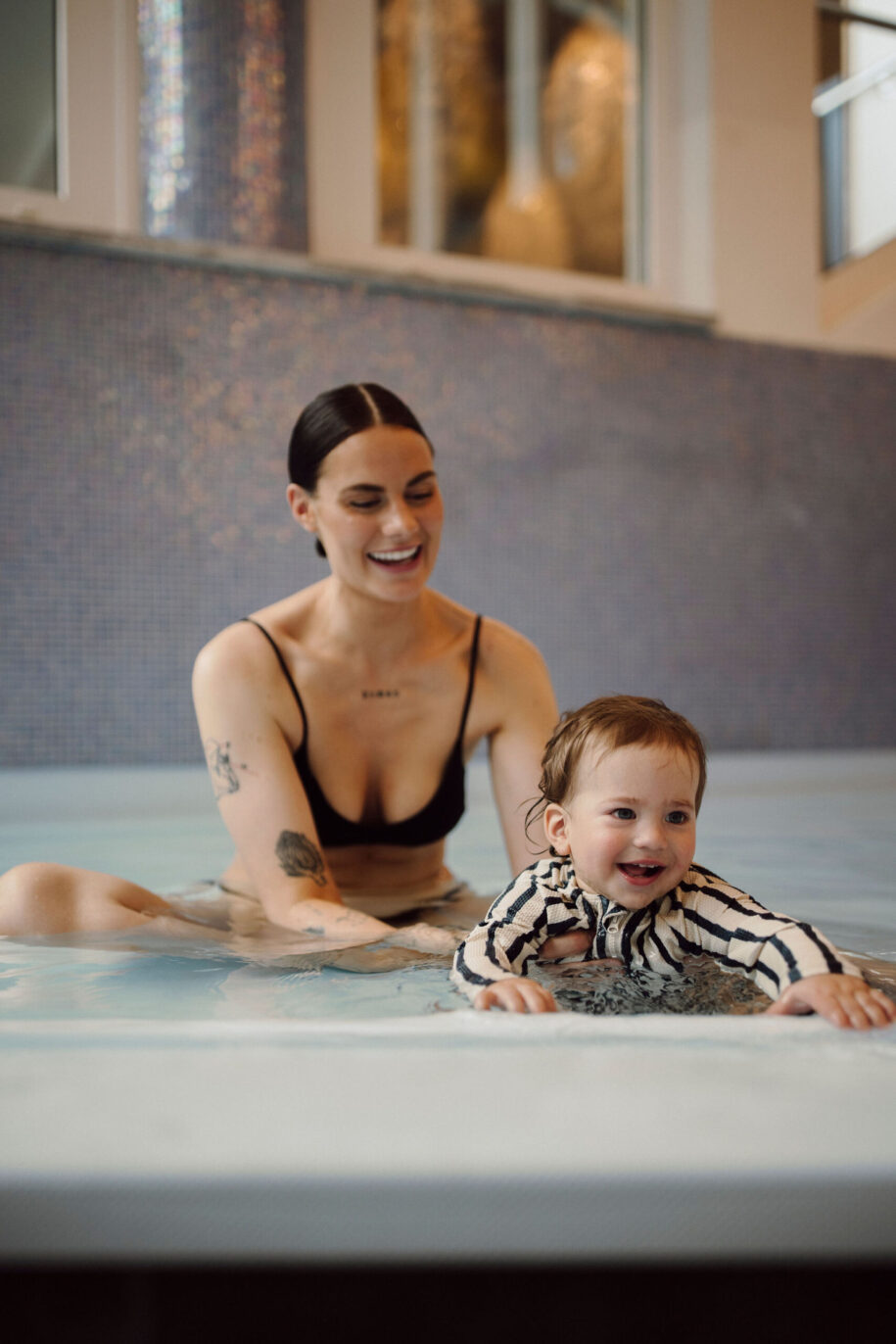 Eine Mutter plantscht mit ihrem Baby im beheiztem Babypool vom Hotel Alpina Alpendorf.