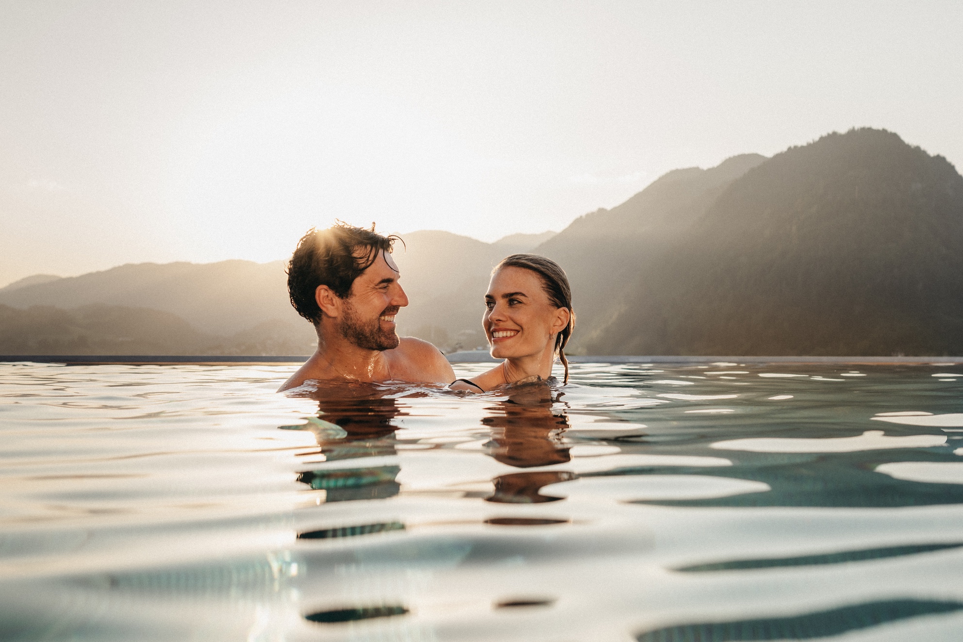 Ein Paar geniesst den Sonnenuntergang vom Infinity Pool im Alpina in Oesterreich.