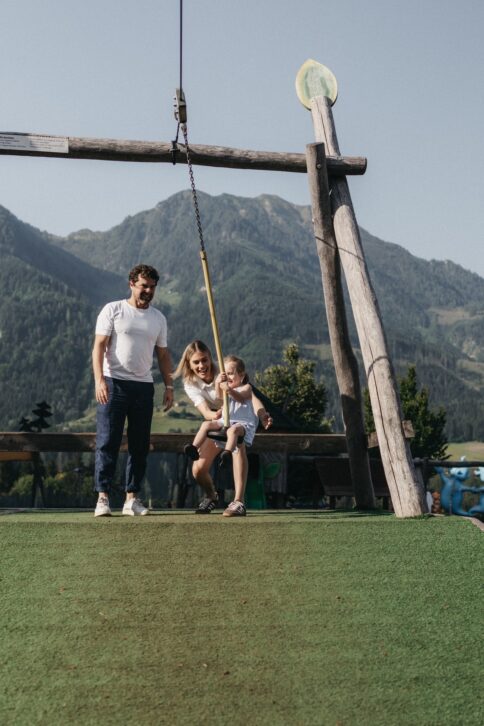 Eine Familie verbringt den Sommertag am Spielplatz beim Hotel Alpina.