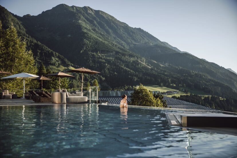 Frau genießt Aussicht im Rooftoppool im Alpina Alpendorf im Salzburger Land