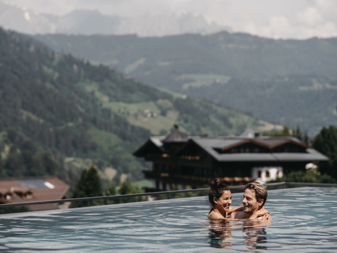 Ein verliebtes Paar verbringt die Zeit im Rooftop Pool im Wellnesshotel Alpina.