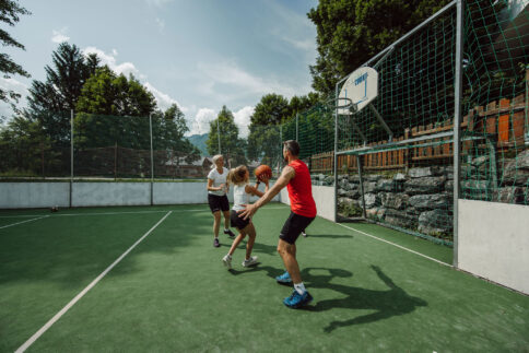 Eine Famiilie spielt Basketball am Funcourt vor dem Familienhotel.