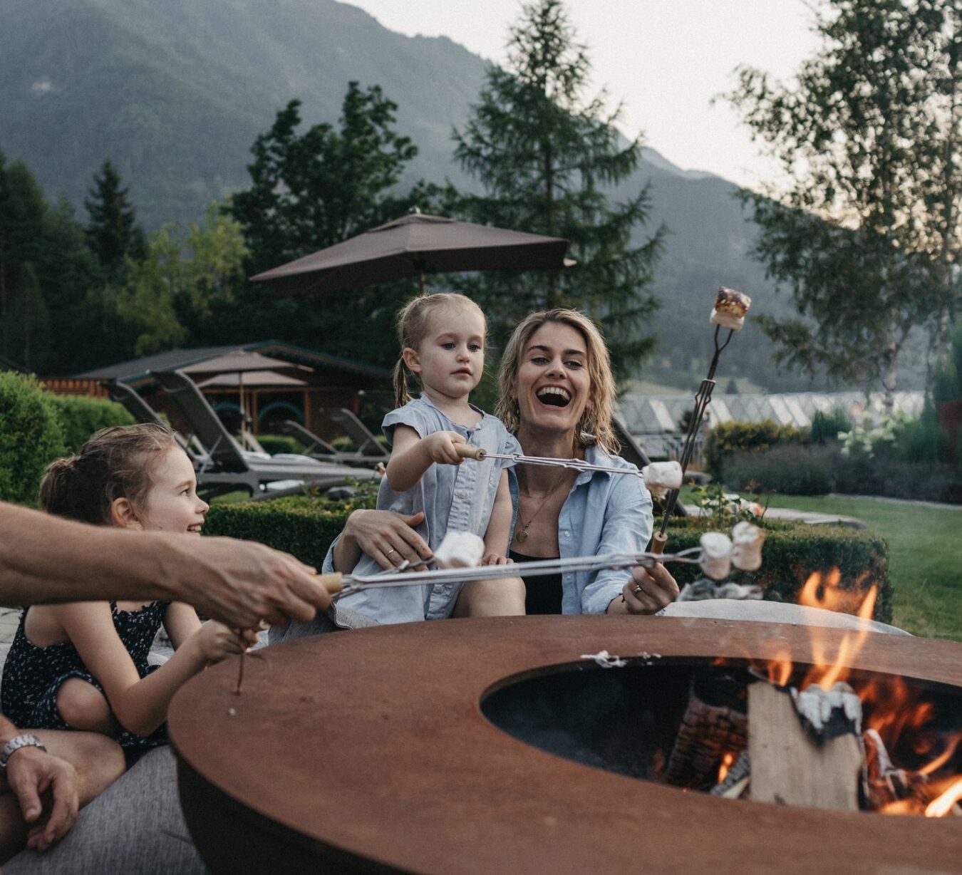 Eine Familie beim grillen an der offenen Feuerstelle im Sommer.