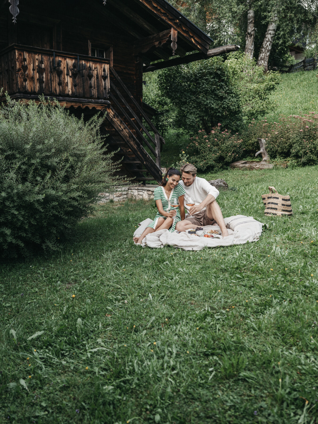 Ein Paar genießt das Picknick auf der Wiese direkt beim Hotel Alpina Alpendorf
