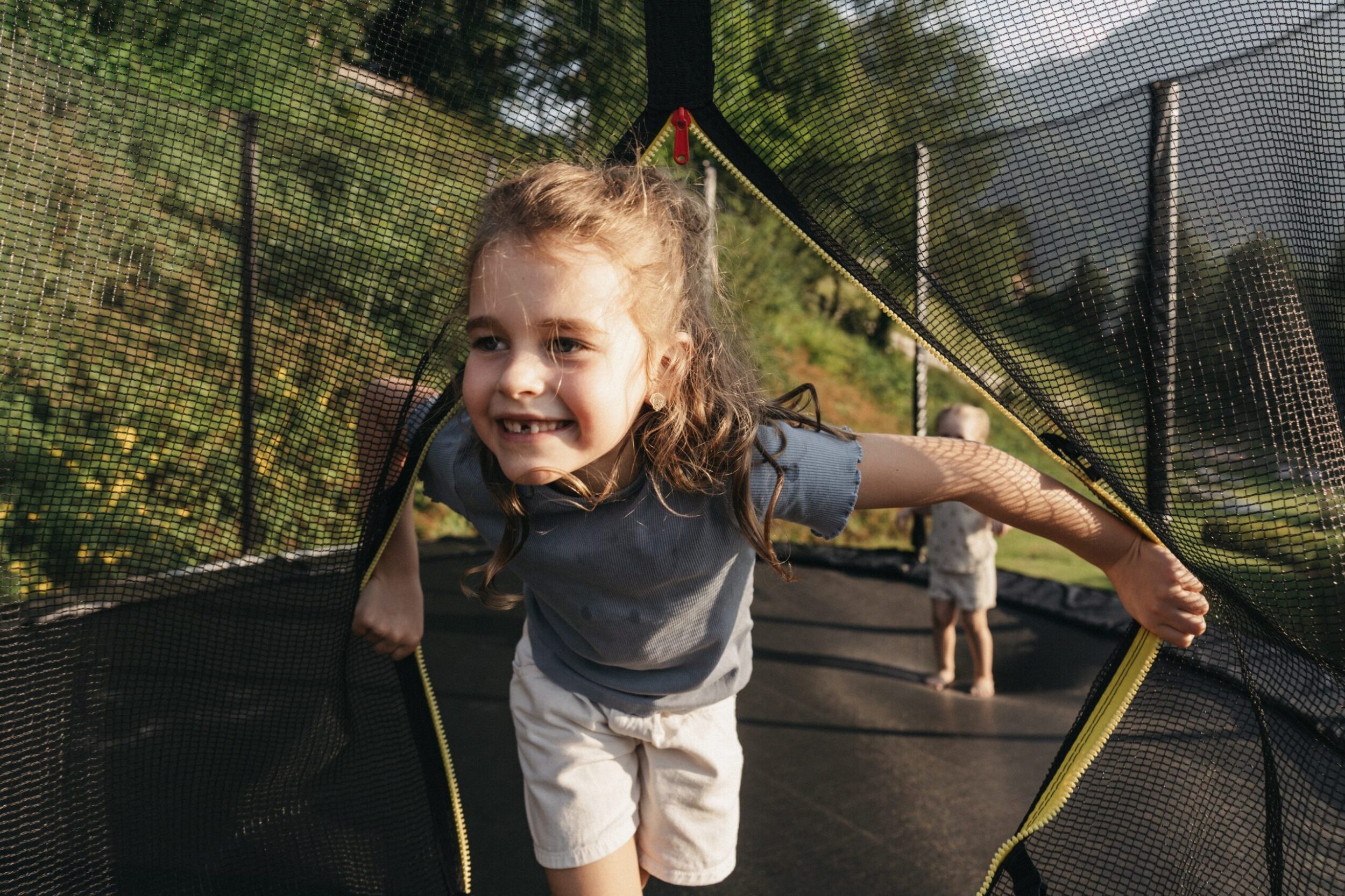 Ein Kind tobt am Trampolin im Garten vom Hotel.