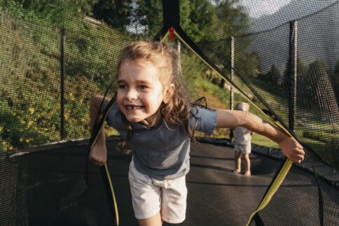 Ein Kind tobt am Trampolin im Garten vom Hotel.