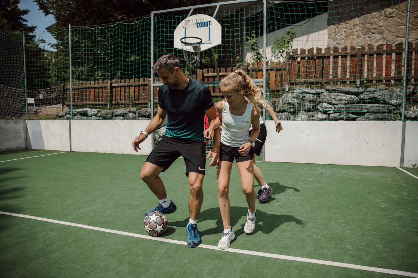 Eine Familie spielt Fussball am Funcoourt vor dem Sporthotel Alpina Alpendorf.