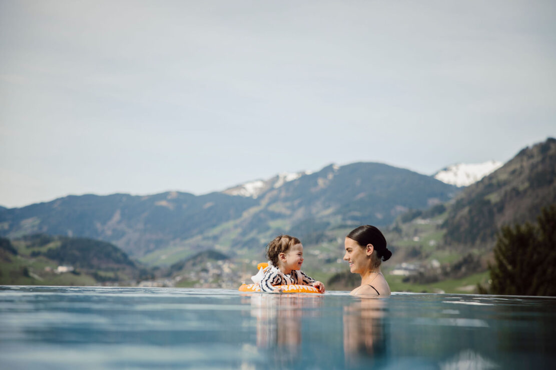 Eine Mama schwimmt mit ihrem Baby im beheiztem Pool vom Hotel Alpina.