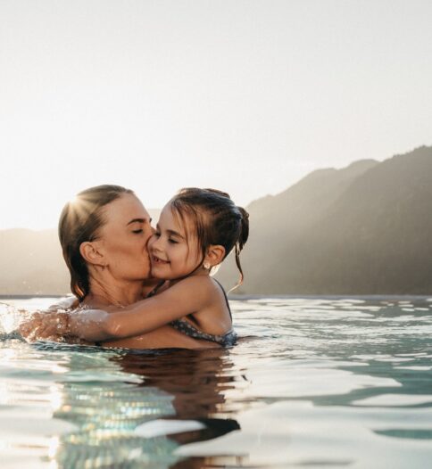Mama und Tochter genießen die Aussicht auf die Bergwelt im Rooftop-Pool im Alpina Alpendorf