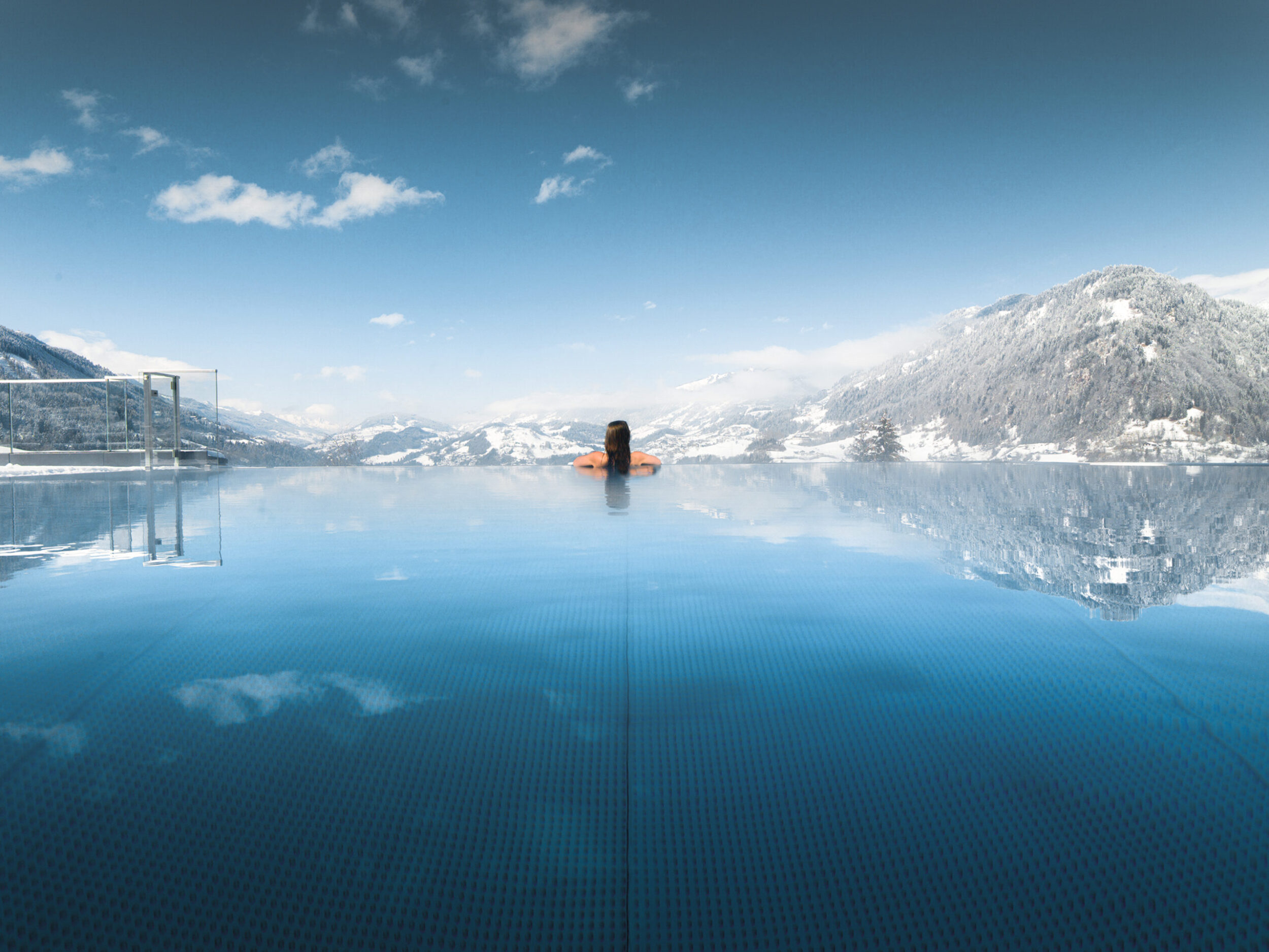 Eine Frau genießt den Winterurlaub im Infinity Pool vom Alpina.