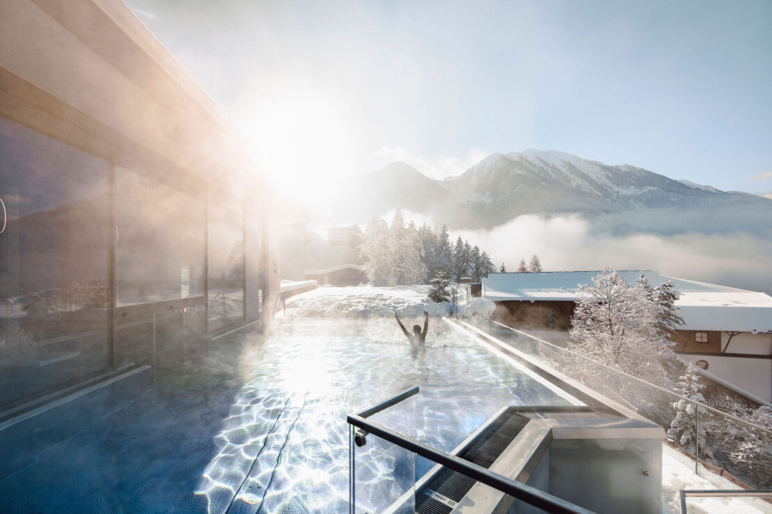Ein Paar geniesst die winterliche Auszeit im Pool vom Alpina Alpendorf.